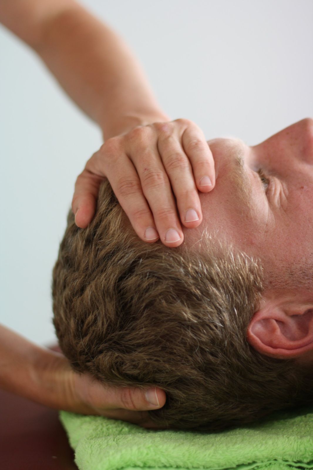 CranioSacral Behandlung: Hände am Kopf eines liegenden Patienten