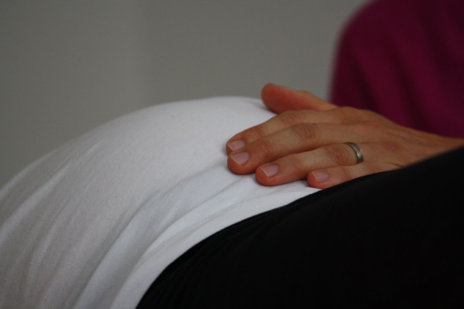 Hand der Therapeutin auf dem Bauch einer Schwangeren